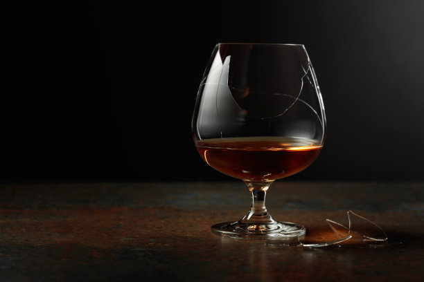 白兰地放在生锈的背景上的碎玻璃里。图片下载