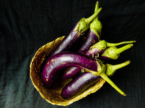 茄子放在黑色背景的木篮子里图片下载