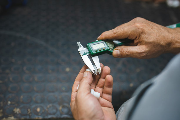 工人用卡尺测量塑料零件图片下载