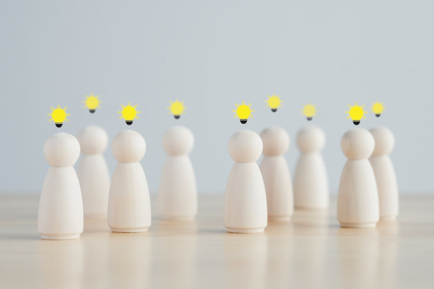 的想法。团队合作。与团队站在一起的木制人物形象，他们有灯泡符号，代表团队的创意。社会关系。领导与领导，协调。创造力。图片下载