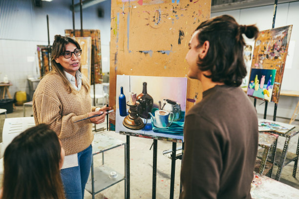 成熟的老师在学校的绘画课上与艺术学生合作-关注老师的脸图片下载
