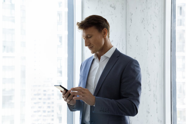 集中的中年商人在办公室使用手机。图片下载