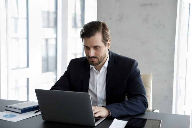 有思想的、专注的年轻男性经理在电脑前工作。图片下载