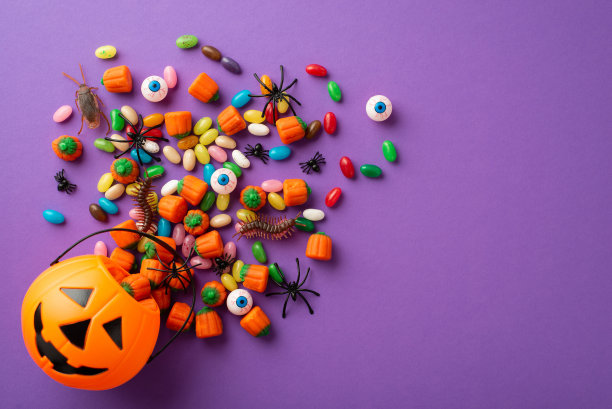 万圣节的概念。俯视图照片南瓜篮子与糖果眼球昆虫蟑螂蜈蚣和蜘蛛在孤立的紫罗兰背景图片下载
