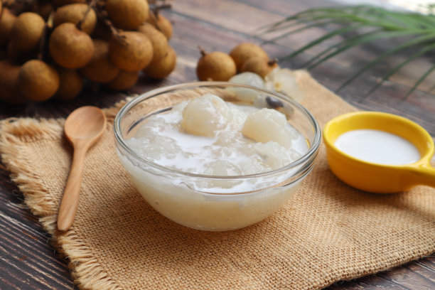 糯米煮在糖浆与龙眼和椰奶酱近距离观察木桌-泰国甜点图片下载