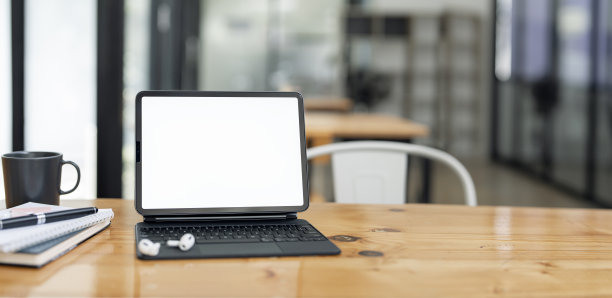 创意工作空间与木制桌子上的空白屏幕平板在阁楼办公室。图片下载