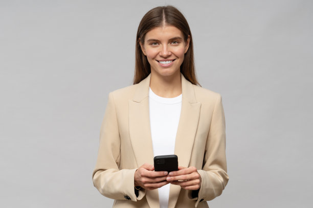 在灰色背景上展示新的商务交流手机应用程序的女商人的肖像图片下载