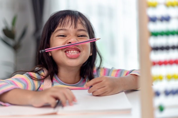 有趣的女孩玩拿笔在鼻子和嘴唇之间的胡子看着镜头，好玩的无聊后学习了很长时间。图片下载