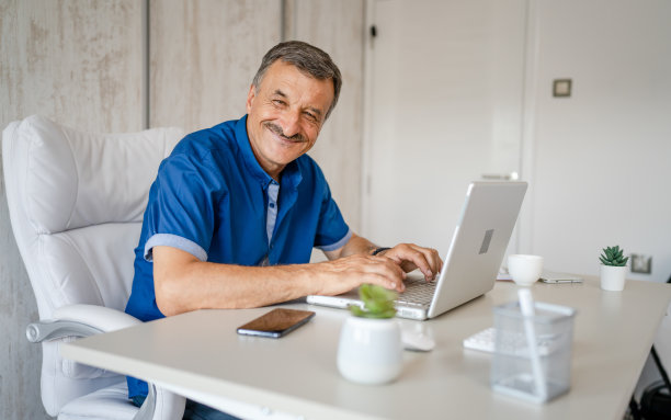 一位资深男性企业家在办公室用笔记本电脑工作图片下载