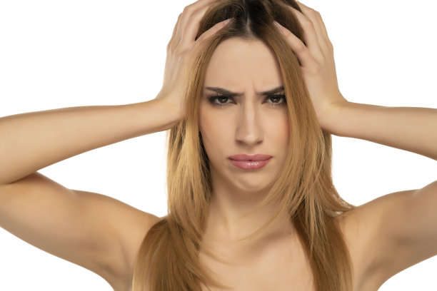 年轻女子看着相机，手捧着头感到不健康的压力图片下载