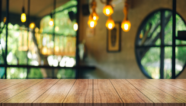 空的木制桌面与灯光散焦模糊的餐厅背景。图片下载