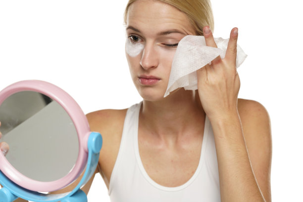 年轻严肃的金发女子用湿纸巾洗脸图片下载