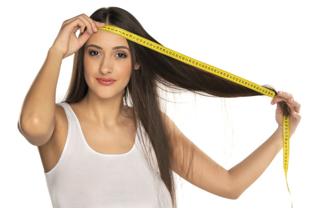 一个年轻快乐的女人用卷尺给我们看她头发的长度图片下载