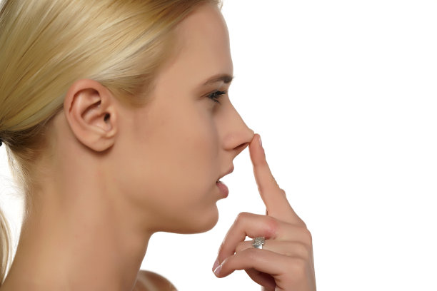 年轻的金发女子用手指摸着鼻子图片下载