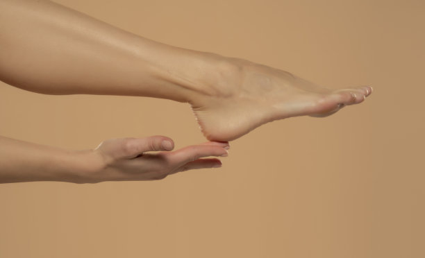 脚后跟皮肤护理，女人触摸健康的脚身体用手，腿超过米色背景图片下载