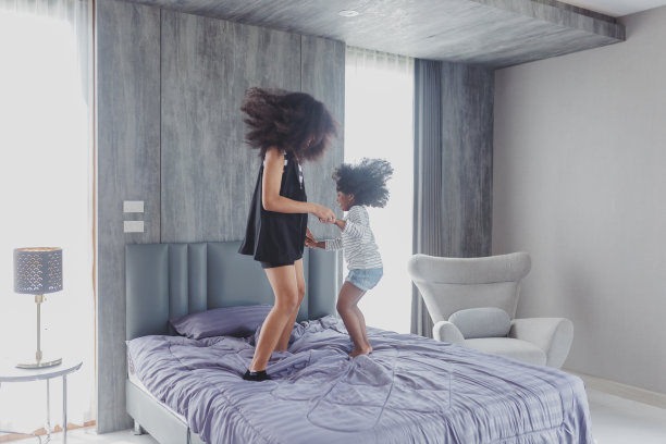 可爱的小孩在家里的床上跳。妹妹在床上跳起来，笑了。图片下载