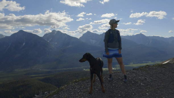 女子竞跑者与狗在山脊上停留图片下载