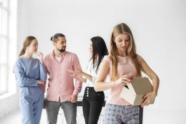 女人在办公室打开礼品盒。一群雇员。圣诞节惊喜和礼物的概念。图片下载