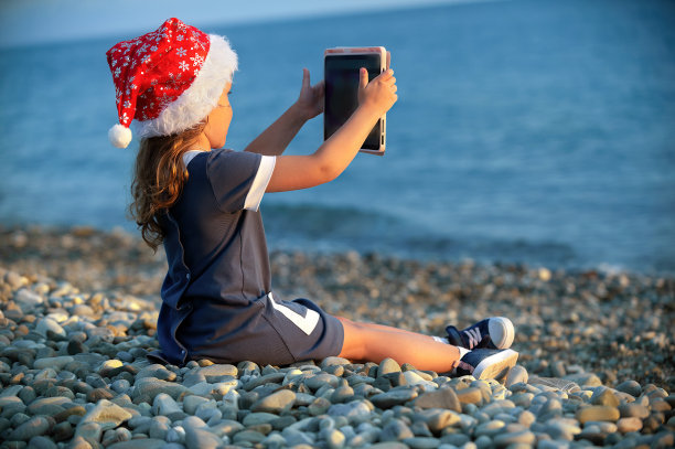 孩子们戴着圣诞老人的帽子在海边玩耍图片下载