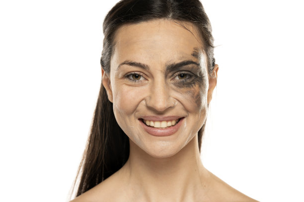 一个年轻的微笑的女人在白色的背景下，半脸脏，半卸妆图片下载