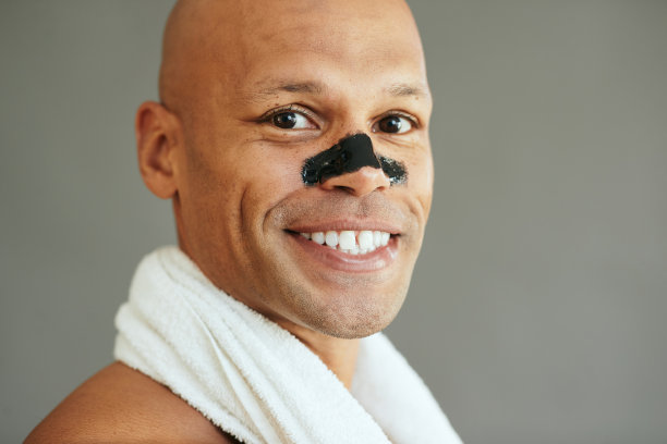 年轻快乐的黑人男子用木炭清洁鼻子条看着镜头。图片下载