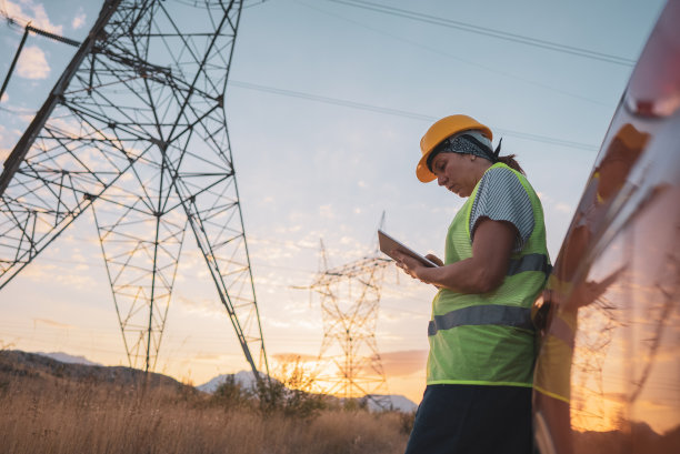 女电气工程师在高压塔附近工作图片下载