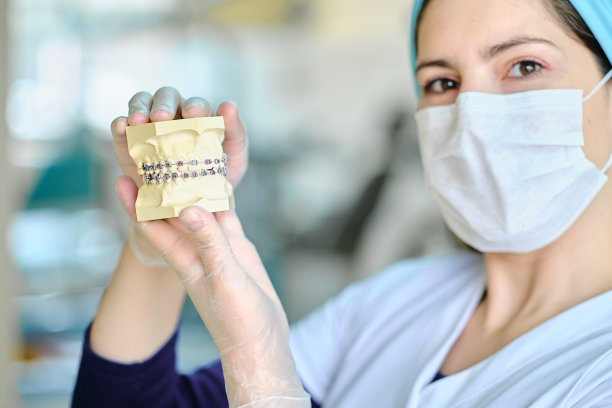 拿着带托槽的假牙的牙医，特写。图片下载