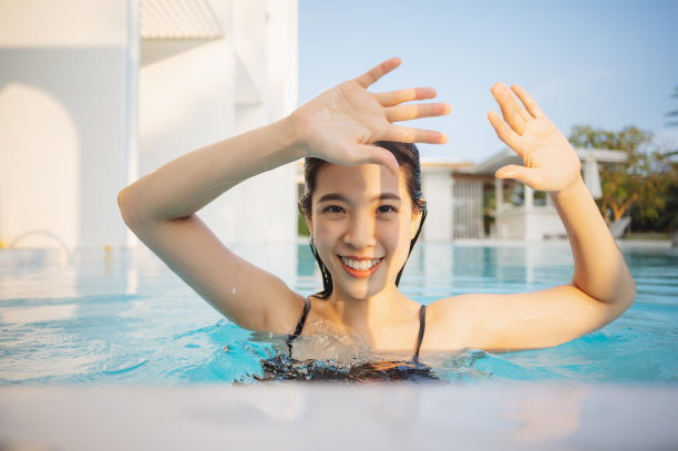 一个美丽的女人的肖像在游泳池里看着相机，放松地看着相机在夏天度假的热带水疗中心，她高兴的防晒乳液在她的脸上图片下载