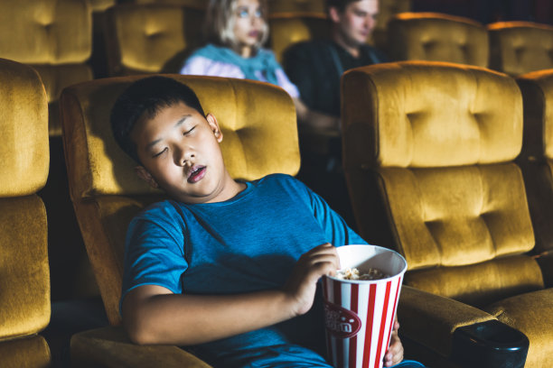 亚洲小男孩看完电影后在电影院睡觉。图片下载