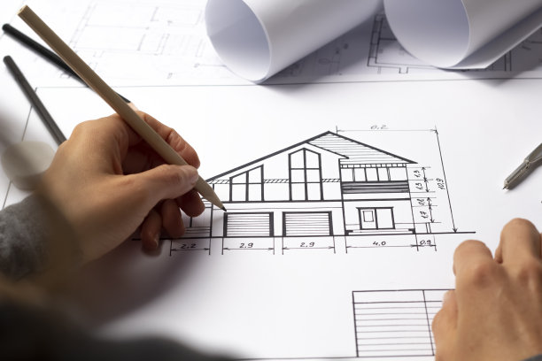 女建筑师在纸上画房子的草图。一位设计师正在他的办公桌上做一个建筑项目。蓝图。图片下载