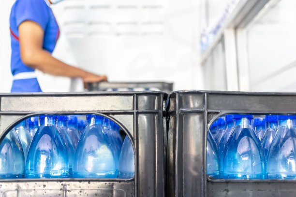 图为，清洁饮用水生产企业清洁饮用水工厂生产饮用水的工人正在将蓝色水瓶包装成饮用水产品图片下载