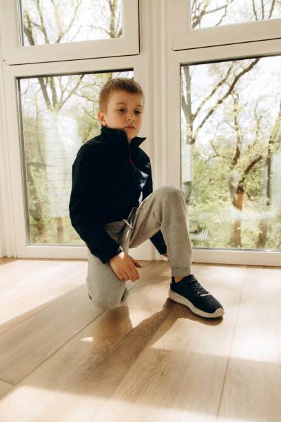 心烦意乱、若有所思的6-7岁男孩坐在窗边。男孩的肖像图片下载