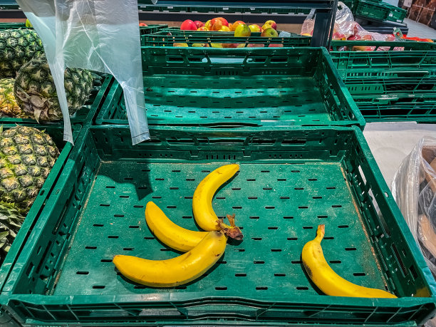 几个新鲜的香蕉水果在一个空的绿色塑料超市盒子里。展示蔬菜店。图片下载
