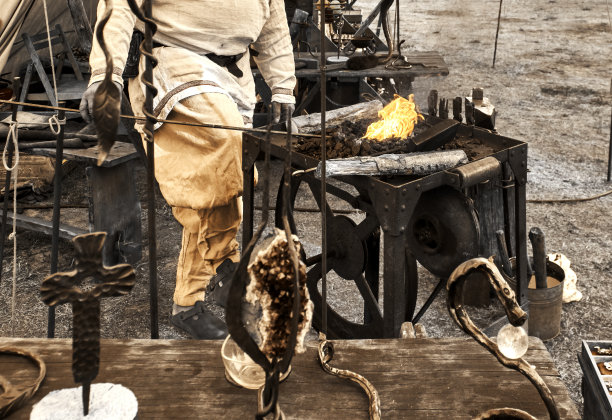 燃烧木炭的古代锻炉煤盆视图，前景故意模糊的工件图片下载