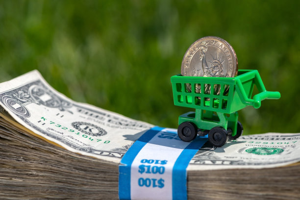 一枚美元硬币和一辆微型购物车在一堆旧美国钞票上图片下载
