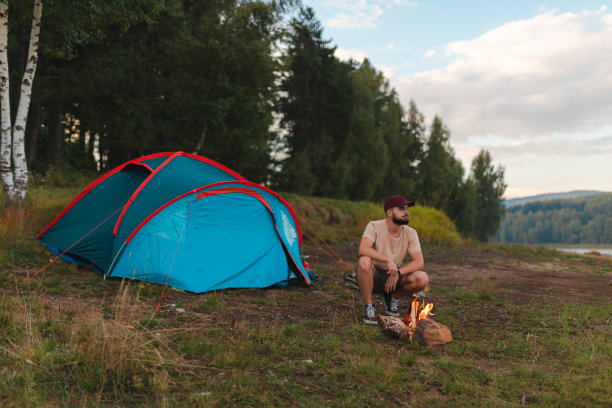 一名年轻人在户外露营时在帐篷外燃起营火图片下载