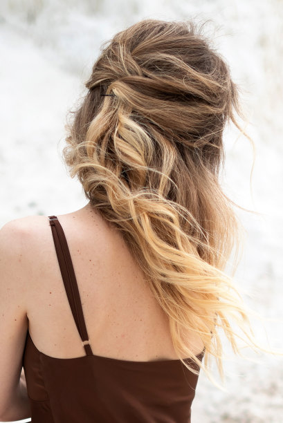 年轻女子与长长的金色发型穿着棕色丝绸连衣裙站着转身图片下载