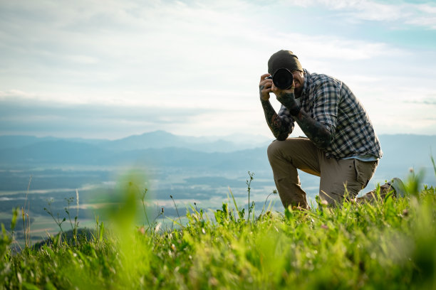 摄影师用无反光镜相机拍摄照片的侧视图，看着相机。图片下载