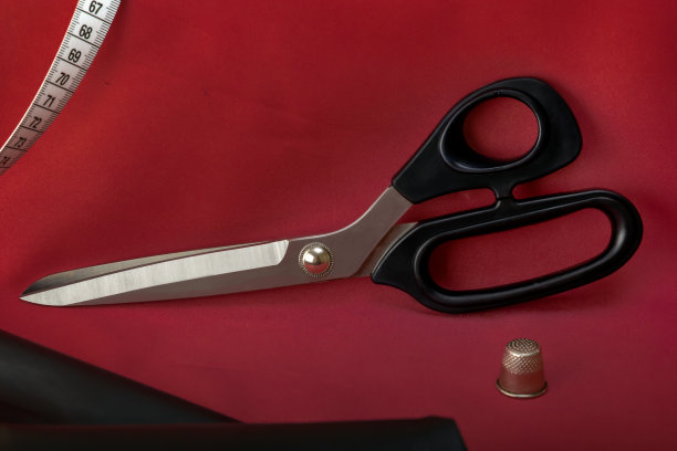裁缝的剪刀放在一块空白的布料上，背景是缝纫配件。特写镜头。图片下载