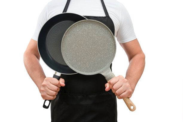 一个男人的躯干在黑色围裙和煎锅在他的手在一个白色孤立的背景。烹饪的概念图片下载