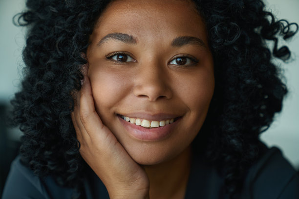 迷人的女人把手放在她的脸颊上，看着镜头图片下载