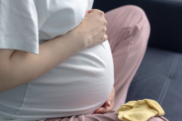 一个在家休息的孕妇抚摸她的大肚子，靠近。图片下载