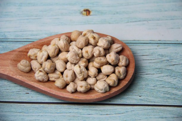 鹰嘴豆(西塞鹰嘴豆)，放在木勺里，孤立在木桌上，俯视图。图片下载