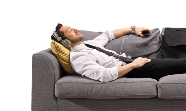 穿着正装的年轻人躺在沙发上听音乐图片下载