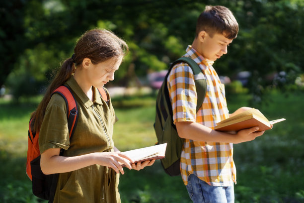在城市公园里的学生肖像，十几岁的学童一个男孩和一个女孩走在穿过公园的小路上，阅读书籍，教育和回到学校的概念图片下载