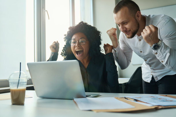 电脑旁的经理们为一笔成功的交易而欢欣鼓舞图片下载