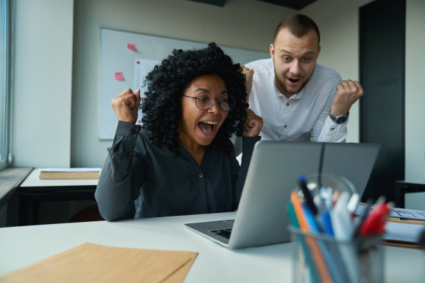 电脑旁的男女为一笔成功的交易而欢欣鼓舞图片下载