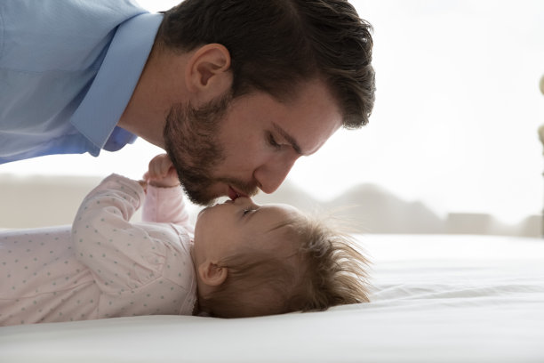近距离观察年轻慈爱的父亲亲吻可爱的婴儿女儿图片下载