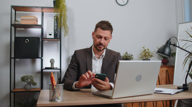 商人在办公室用笔记本电脑工作，戴着耳机听着最喜欢的充满活力的迪斯科音乐图片下载