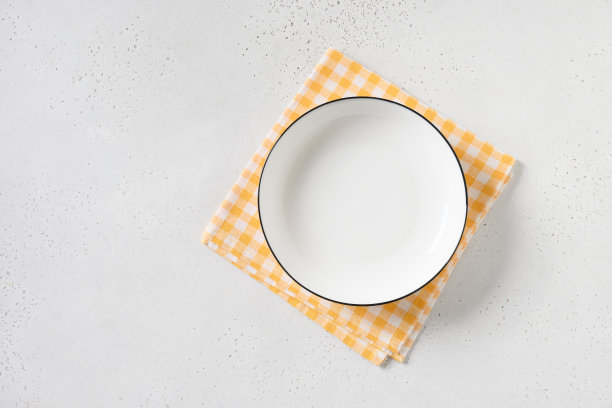 白色空盘子，白色背景上有黄色格子毛巾。图片下载